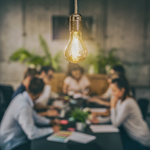 Young business people are discussing together a new startup project. A glowing light bulb as a new idea.