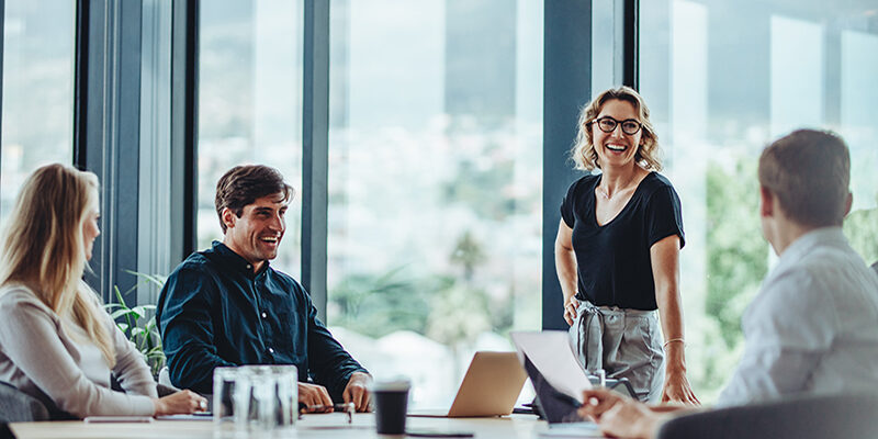 Office colleagues having casual discussion during meeting in conference room. Group of men and women sitting in conference room and smiling.