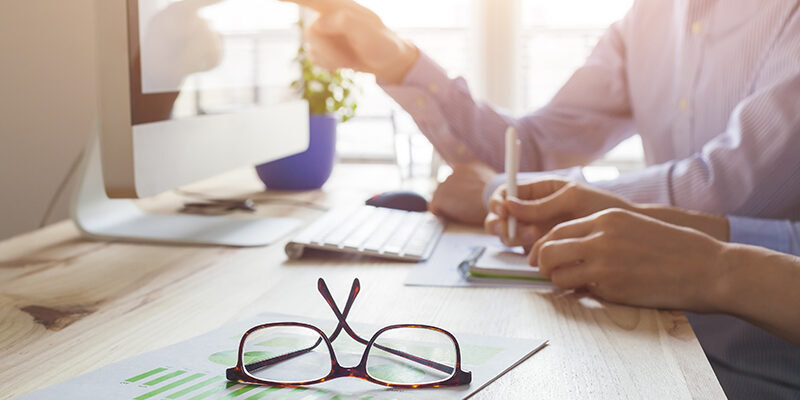 Sunset atmosphere in co-working office, business meeting with two people, close-up on glasses
